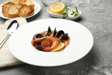 Delicious seafood soup served on gray textured table, closeup