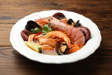 Delicious seafood soup in bowl on wooden table, closeup