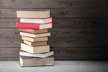 Stack of old books on grey wooden table, space for text