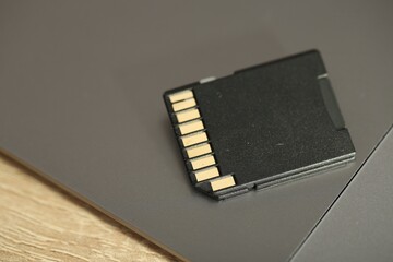 SD memory card and laptop on wooden table, closeup