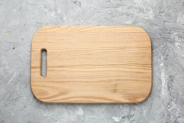 One wooden serving board on light grey textured table, top view. Space for text