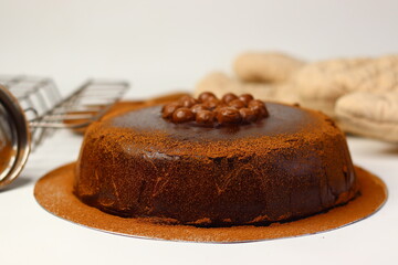Rich chocolate cake topped with crunchy chocolate coated nuts, dusted with cocoa powder