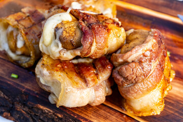 Savory meat rolls cooked on a wooden board in outdoor setting