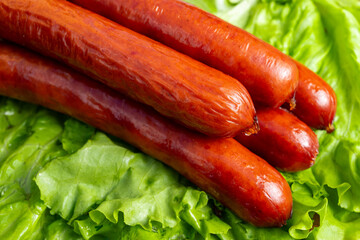Sizzling sausages resting on fresh green lettuce leaves