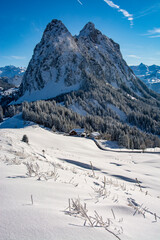 The large and small Mythen mountains photographed on a snowshoe tour at Haggenegg. With a freshly snow-covered landscape and the approaching sunset.