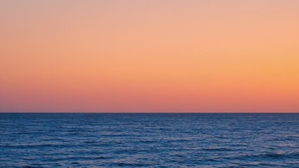 Fototapeta premium A serene ocean sunset with a calm horizon and clear water.