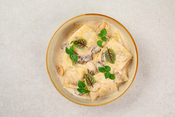 Portion of gourmet ravioli with cream sauce and olives