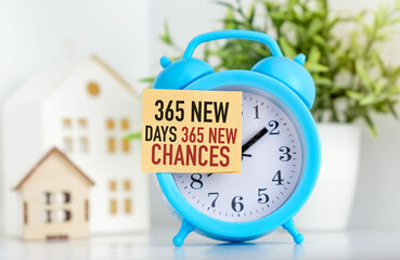 A blue alarm clock with a red and white sign that says 365 new days