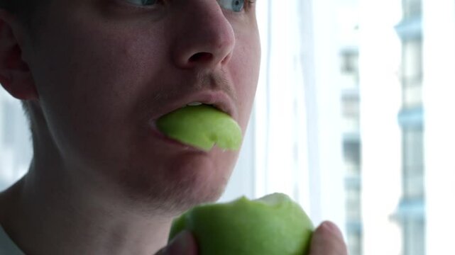 A man in front of the camera eats a sour apple.
Ripe fruits.
A man with an apple.
A man bites an apple with his teeth