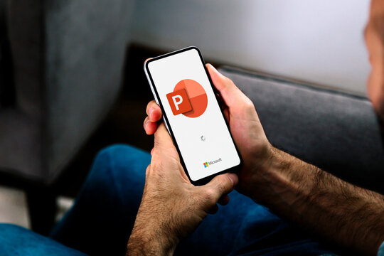 Man using a mobile phone displaying logo of Microsoft Office PowerPoint on the screen. Power point is a presentation program. ROSARIO, ARGENTINA - APRIL 5, 2025.