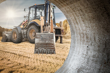 Construction equipment digging in rental site with large concrete pipe during daytime in urban area
