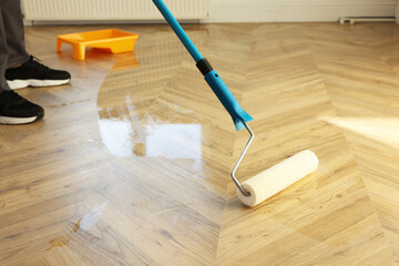 Man polishing parquet with varnish indoors, closeup