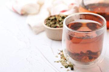 Delicious herbal tea and dry leaves on white table, closeup. Space for text