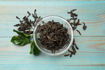 Dried and fresh tea leaves on blue wooden table, top view