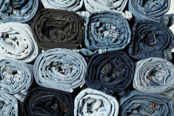 Different stylish rolled jeans as background, top view