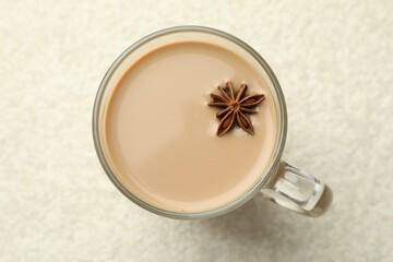 Aromatic Masala tea with anise star in glass cup on white textured table, top view