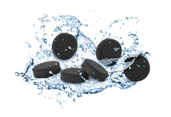 Activated charcoal pills and splashes of water in air on white background. Effective sorbent