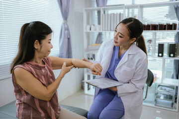 A female doctor performs a physical examination and physical therapy on an elderly woman at home.
