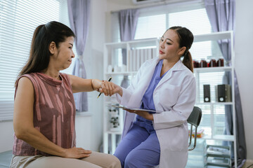 Obraz premium A female doctor performs a physical examination and physical therapy on an elderly woman at home.