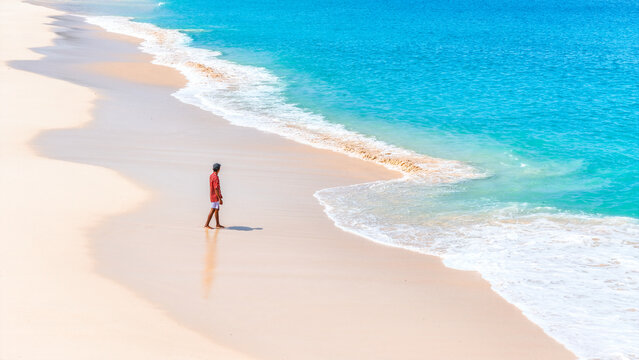 A man enjoys the white sand beach and turquoise waves. summer background and summer holiday concept.