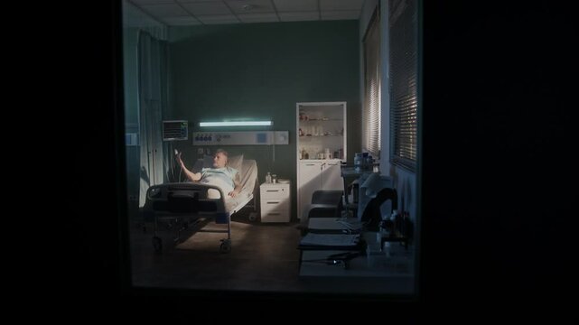 Old patient man with medical dropper lies on clinic ward bed