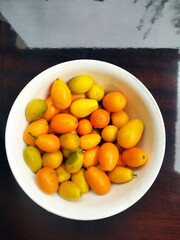 Kumquat Nagami in a white bowl against lacquered table with sky reflection