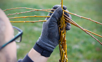 Close-up of a Caucasian man braiding an Easter whip from willow twigs, a traditional Czech and Slovak symbol of Easter, used by boys to carol on Easter Monday.