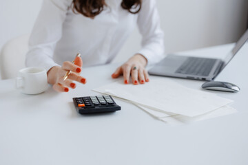 Professional woman calculating finances at a desk with a laptop and documents during a workday