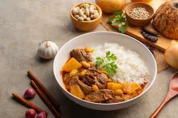 Massaman Curry with beef and cooked rice in white plate.Cooked beef meat and potatoes groundnut...