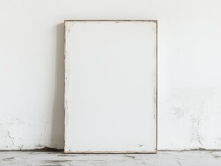 Blank white canvas leaning against textured wall

