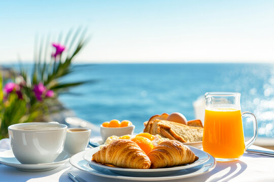Delicious breakfast with croissants, coffee and orange juice overlooking the sea