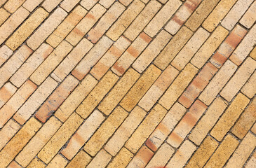 The surface is made of yellow, narrow clinker bricks (tiles) in close-up. Top view