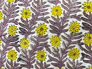 Yellow flowers intertwined with purple creepers bloom across white cotton in delicate hand block...