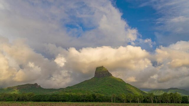 Scenic time lapse of dramatic cloud formation and float quickly around distinctive green mountain. Majestic Rempart mountain peak shrouded in clouds above green valley. 