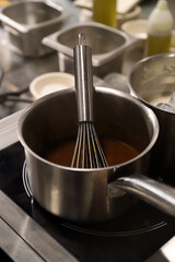 cacerola con chocolate liquido y batidor manual en la cocina