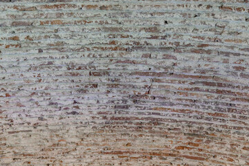 Close-up of an ancient arched ceiling with rough, textured brick and mortar. The weathered patterns reveal craftsmanship and history, shaped by time and elements, illuminated by soft natural light.