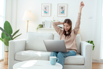 Young Woman Enjoys Working on a Laptop While Sipping Coffee in a Cozy Living Room Setting