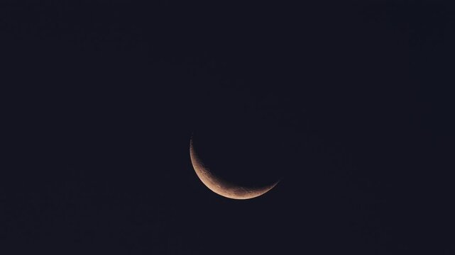 A delicate crescent moon gracefully hanging in the vast blue sky