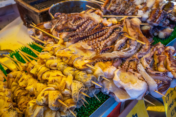 Squid, octopus, seafood and meats grilled in Japanese style in flea market in Japan. Japanese...