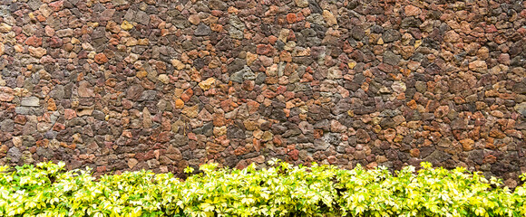 colored unprocessed rocky stones of natural origin, a wall of stones in concrete, background for...