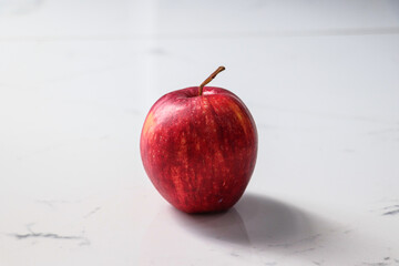 Single Red Apple on White Marble Surface