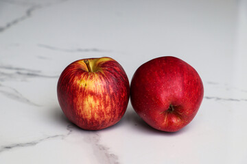 Two Apples Resting on a White Marble Background