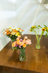 Sunflowers and rose in glass vase on wooden table..