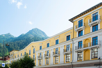 Fototapeta premium a beautiful low-rise yellow building with many windows against the backdrop of mountains in sunny weather