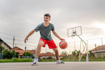 Obraz premium One caucasian teenager stand on basketball court with ball