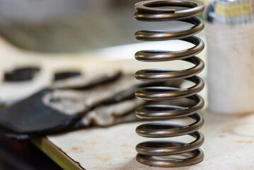 Close-up of a mechanical spring from an onboard device, standing upright on a workbench in the engine room workshop of a cargo ship.