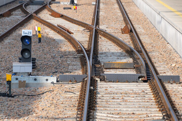 Railway switch with intersecting tracks, gravel bed, signal light, control boxes, and precise rail alignment.
