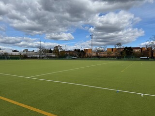 Berlin, Germany – April 05, 2025 Green synthetic turf sports field with white lines under cloudy sky