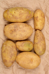 Several potatoes are laid out on brown paper, showcasing their natural texture and earthy tones