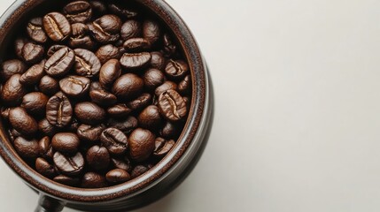 Fototapeta premium A close-up of brown coffee beans placed next to a vintage coffee grinder on a white background